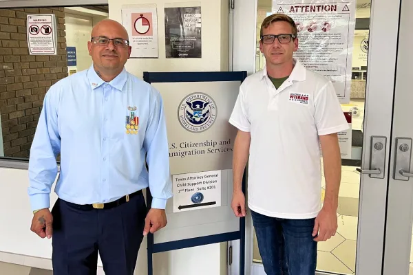 Photo of Ivan Ocon in front of U.S. Citizenship and Immigration Services sign, standing next to man from Union Veterans Council