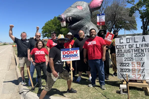 A group of union members poses in front of a Scabby the Rat figure in Forth Worth, Texas.