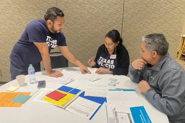 Two AFL-CIO staffers work with a Citizenship Clinic participant to fill out paperwork.