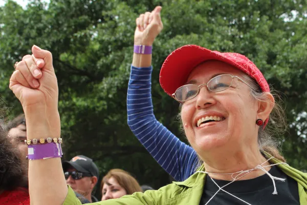 Photo of a person smiling with their right arm upraised.