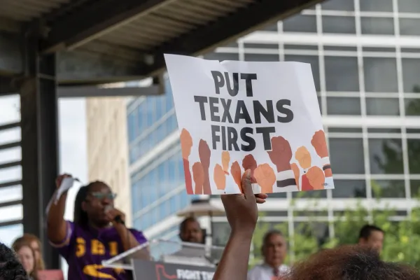 A rally-goer holds up a sign reading "PUT TEXANS FIRST"