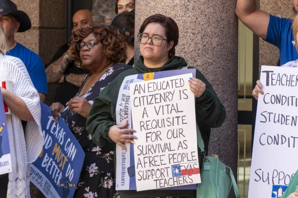 A Texas educator holds a sign at a rally