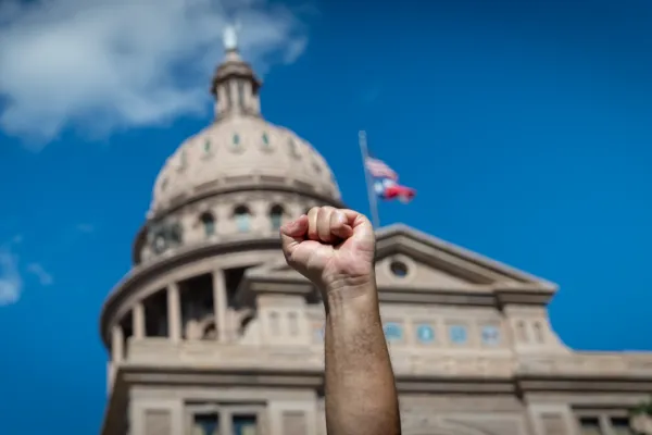 A fist is raised in front of the Texas Capitol dome