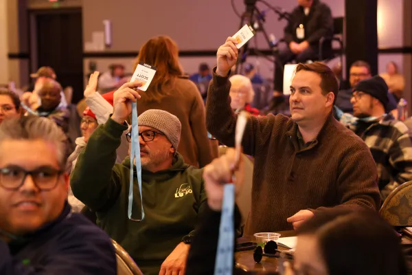 2026 COPE Convention attendees raise their badges to vote