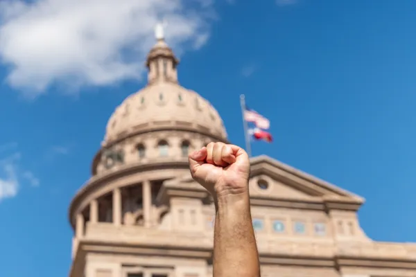 A defiant fist is raised in front of the Texas Capitol