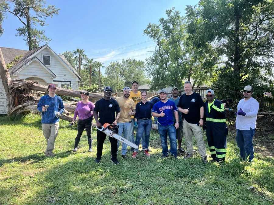 A group of union volunteers pose in front of a yard they cleared of debris from Hurricane Beryl.