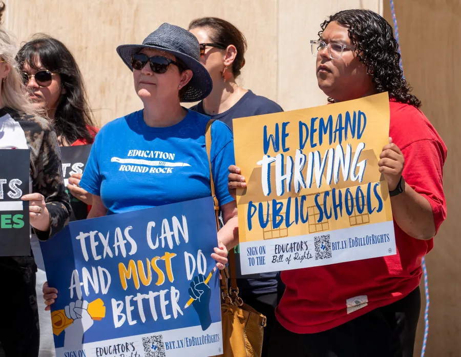 Teachers hold signs with text reading "Texas can and must do better" and "We demand thriving public schools"