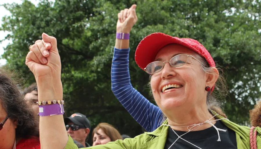 Photo of a person smiling with their right arm upraised.