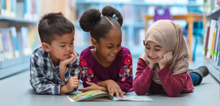 Three kids reading a book together