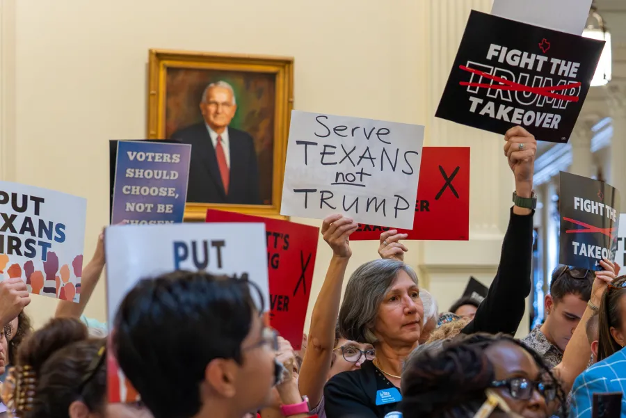 Protestors hold signs at the Texas Capitol, some reading "Fight the Trump Takeover"