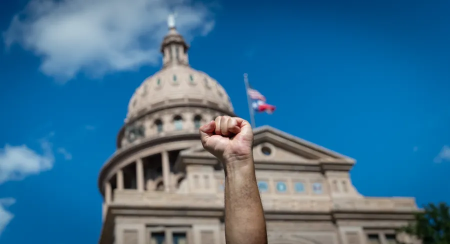 A fist is raised in front of the Texas Capitol dome