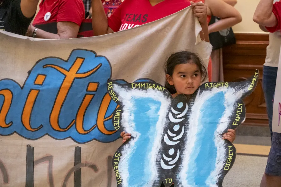 A young girl holds a butterfly