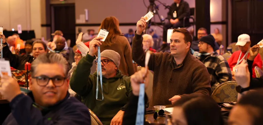 2026 COPE Convention attendees raise their badges to vote