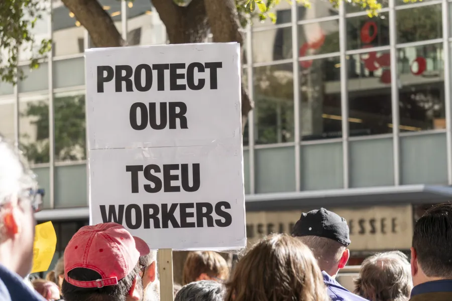 Protestors gather in support of TSEU workers. One participant holds a sign that says "Protect Our TSEU Workers"
